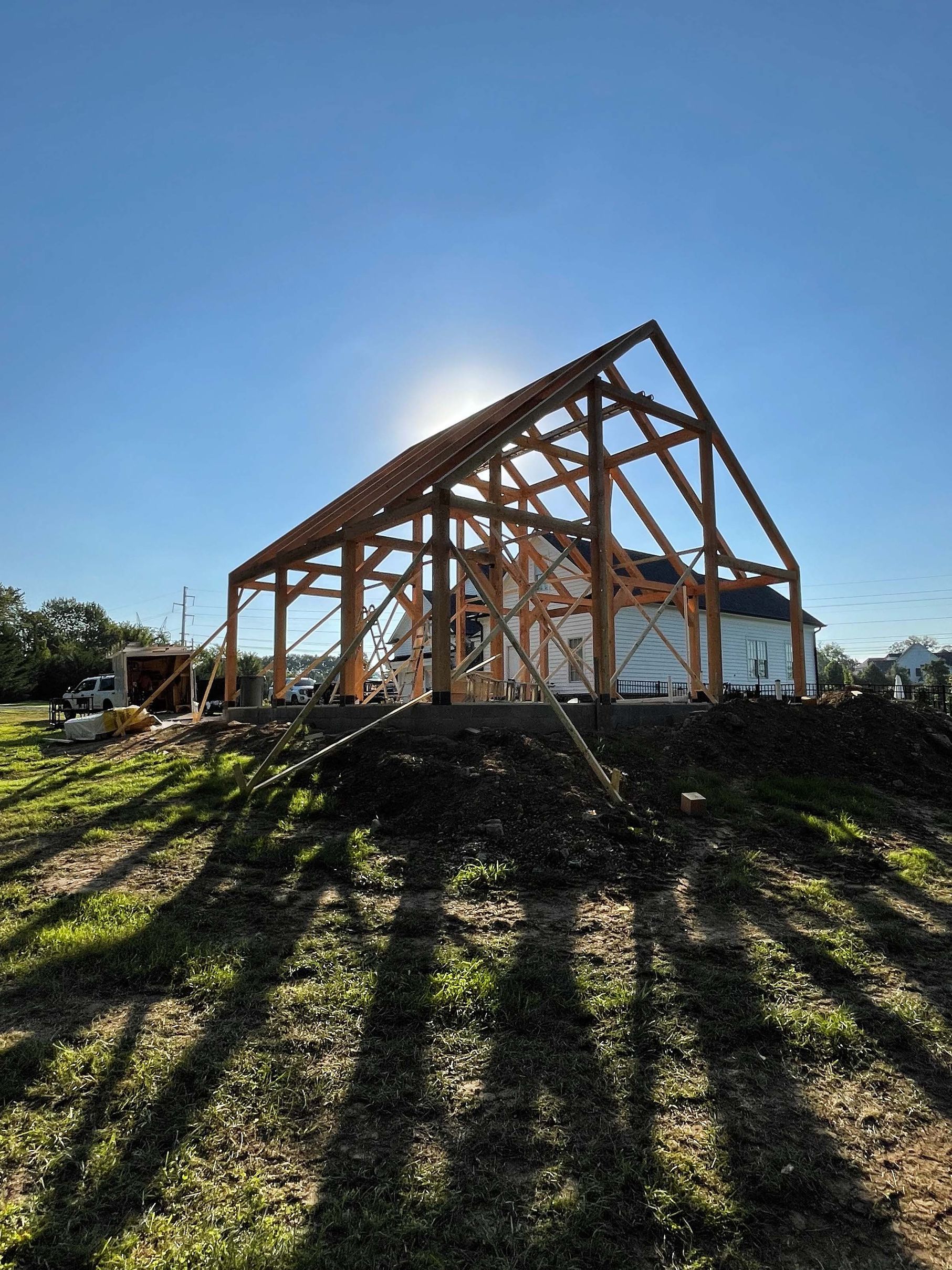 A large wooden barn is being built in a field.