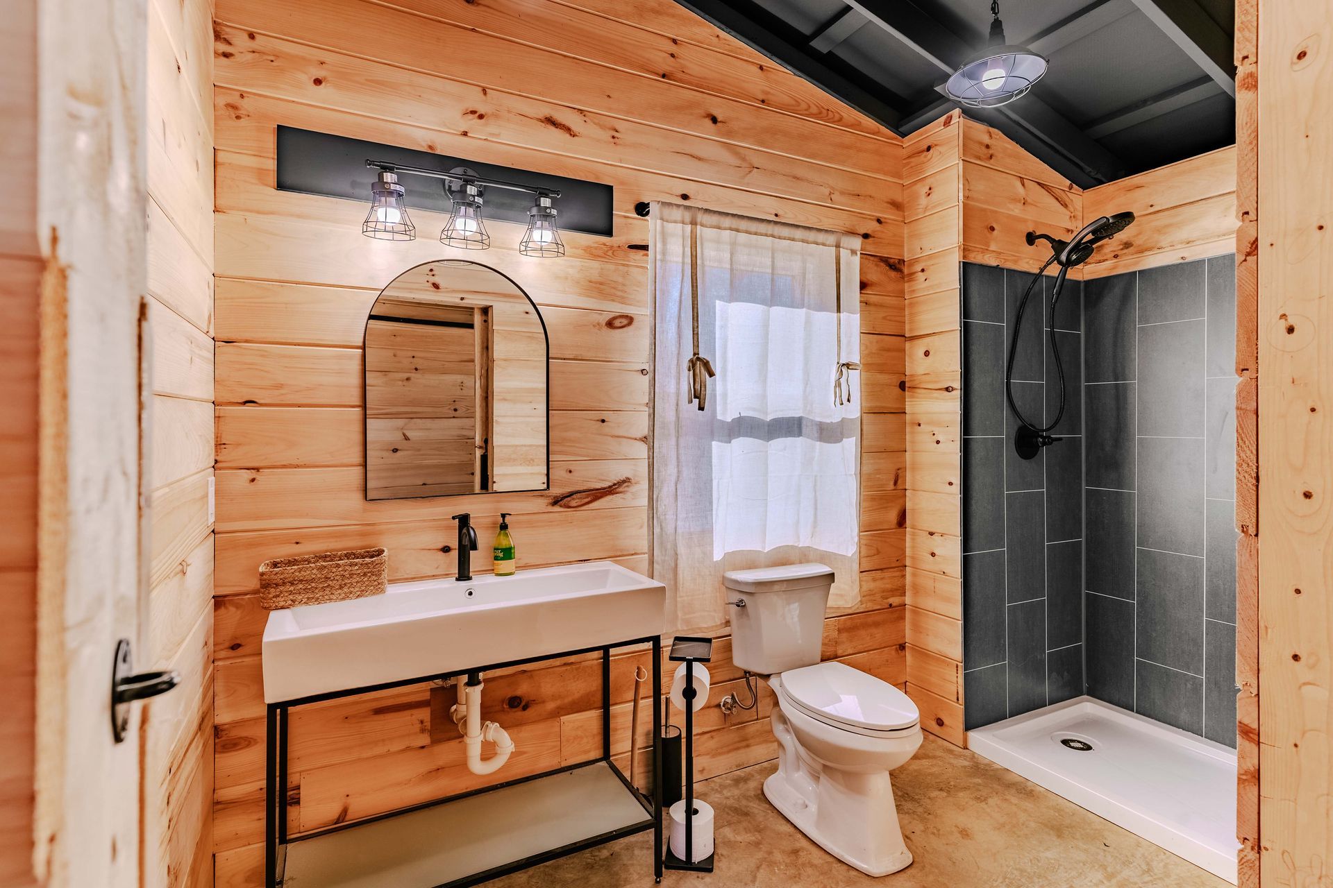 A bathroom in a log cabin with a toilet , sink and shower.