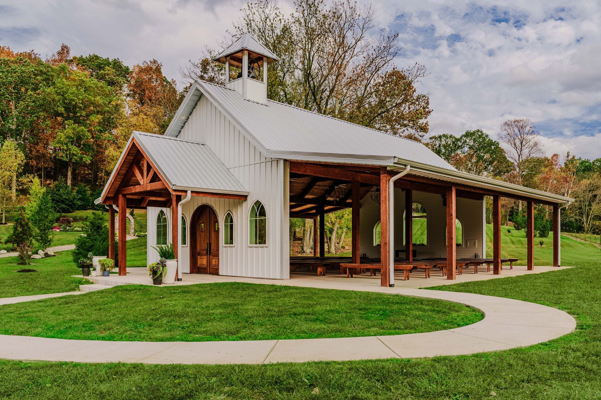 A white barn with a wooden porch and a walkway in front of it.