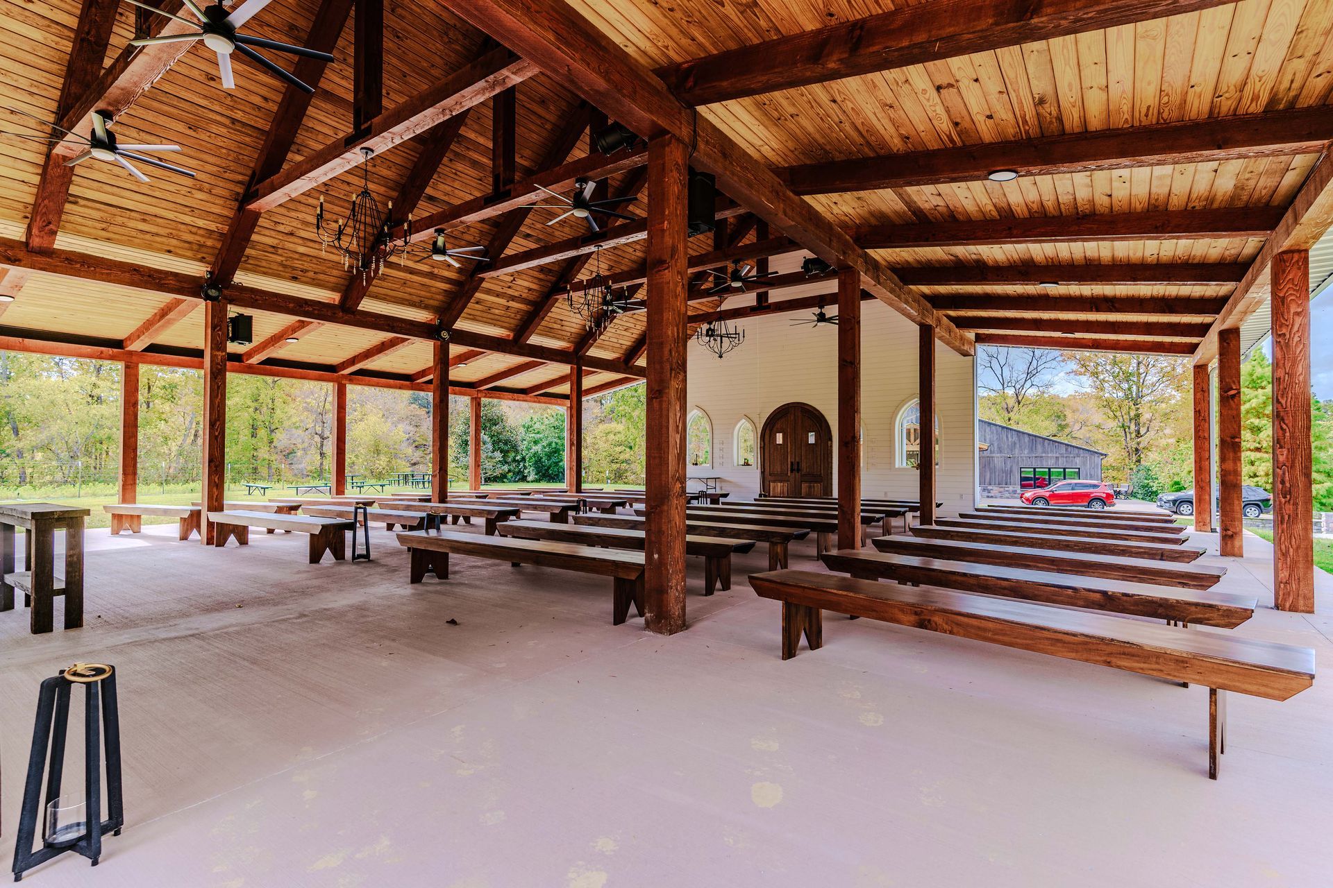 A large pavilion with wooden benches and tables under a wooden roof.