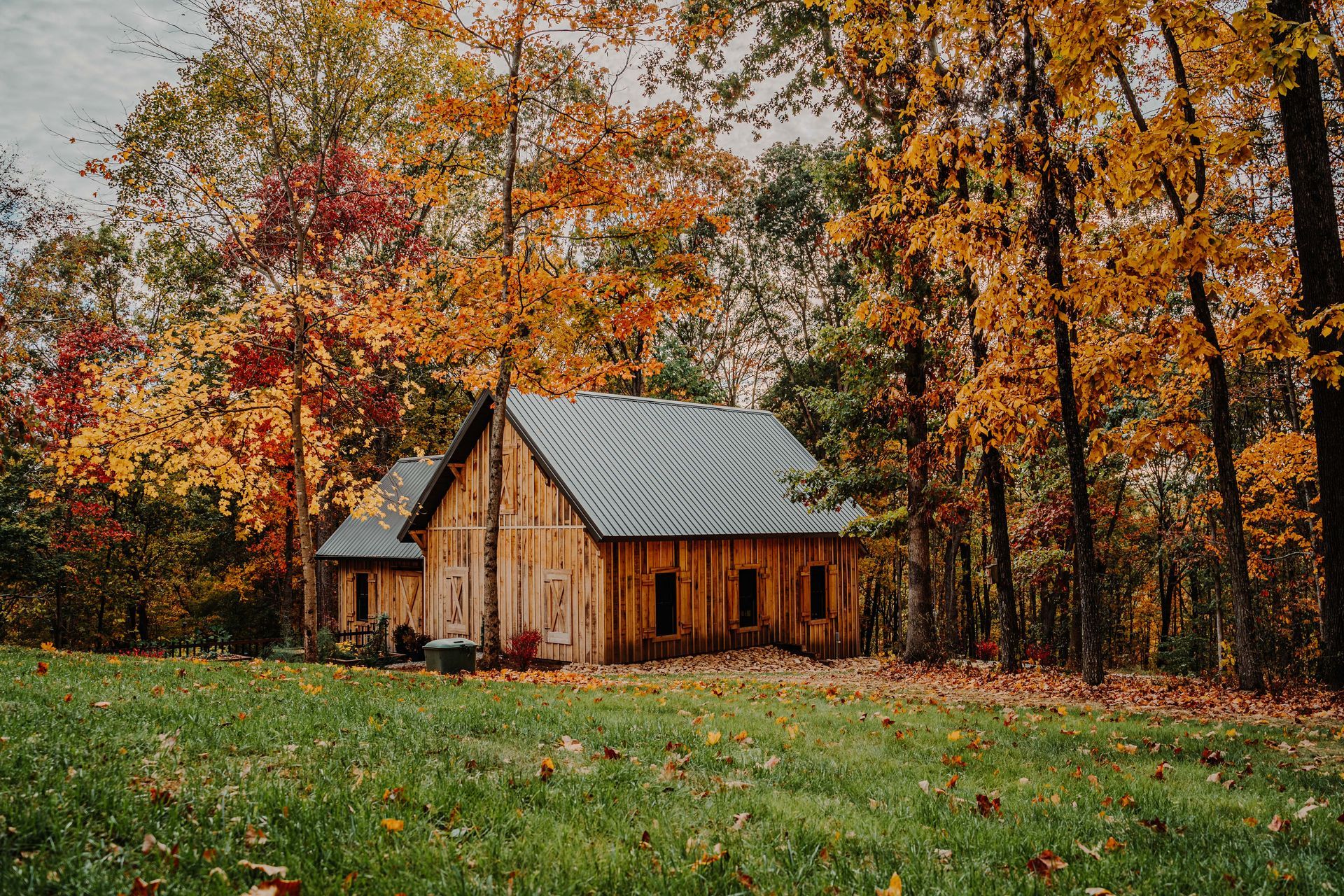A small wooden house is sitting in the middle of a lush green field surrounded by trees.