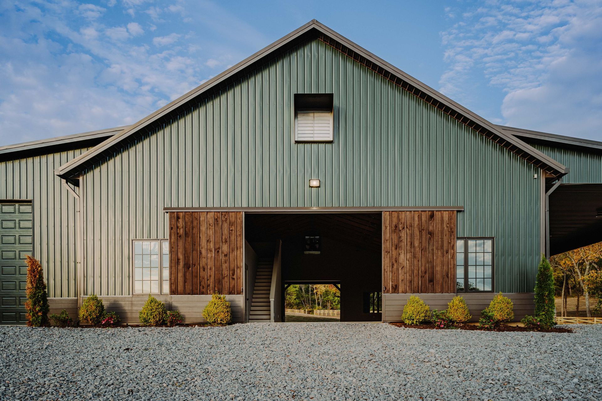 A large green barn with a wooden door and stairs leading to it.