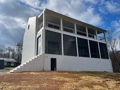 A large white house with a screened in porch and stairs.