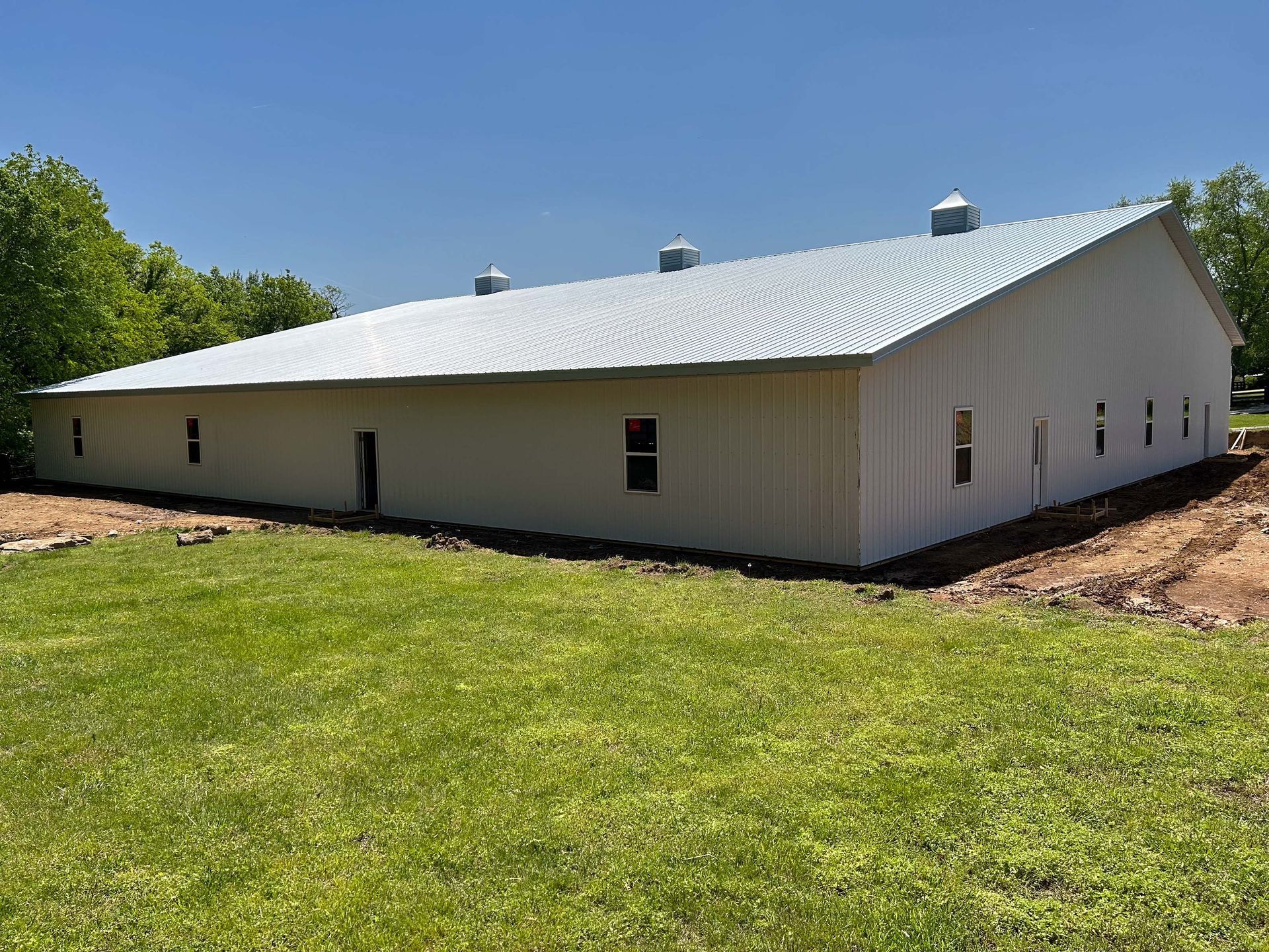 A large white building is sitting in the middle of a grassy field.