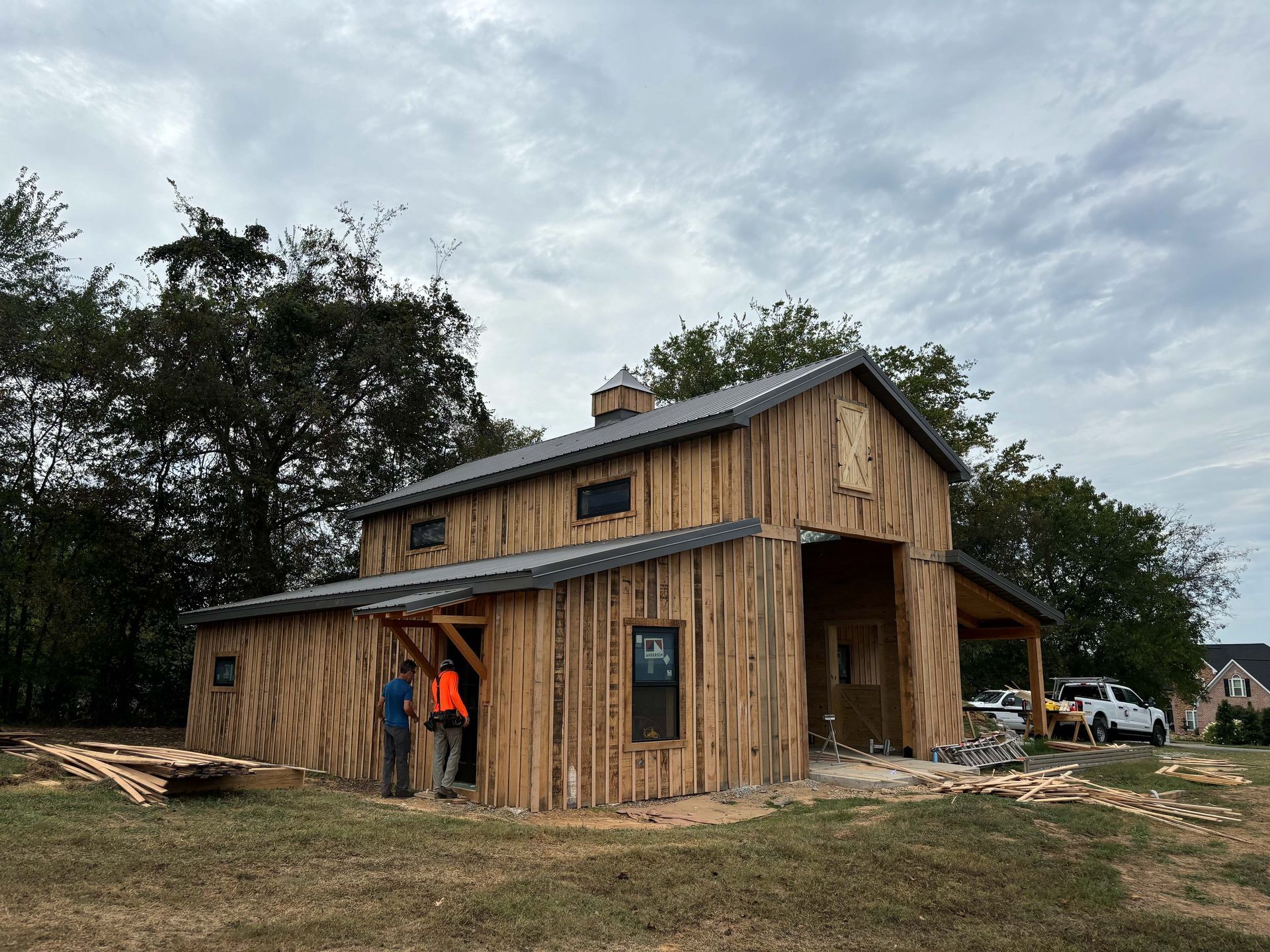 A large wooden barn is being built in a field.