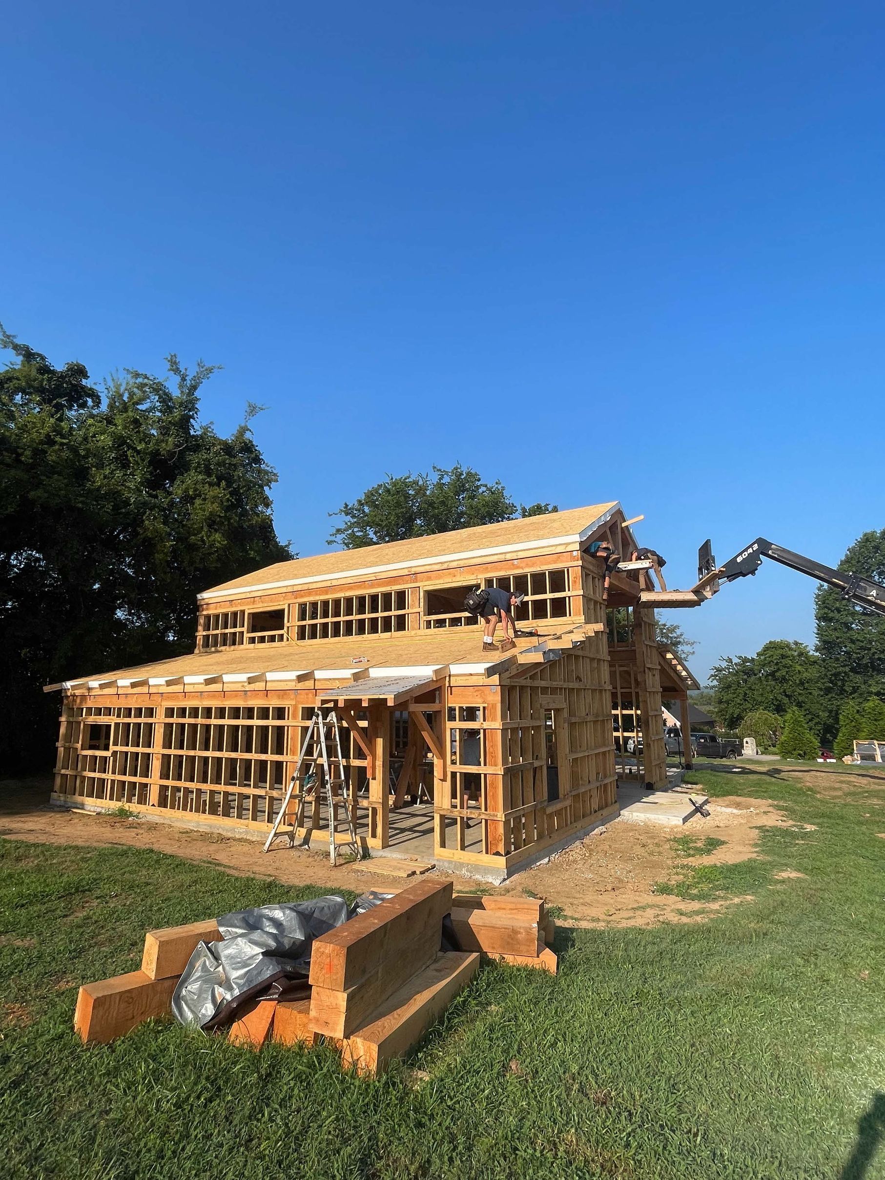 A wooden house is being built in a grassy field.