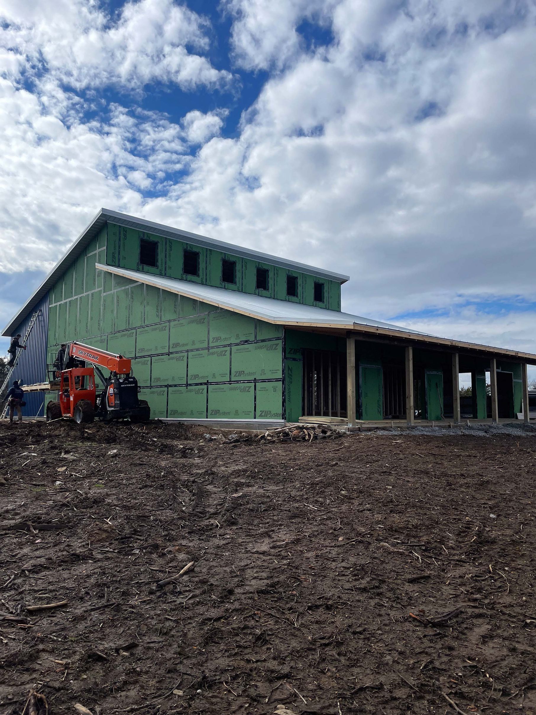 A large house is being built in a dirt field.