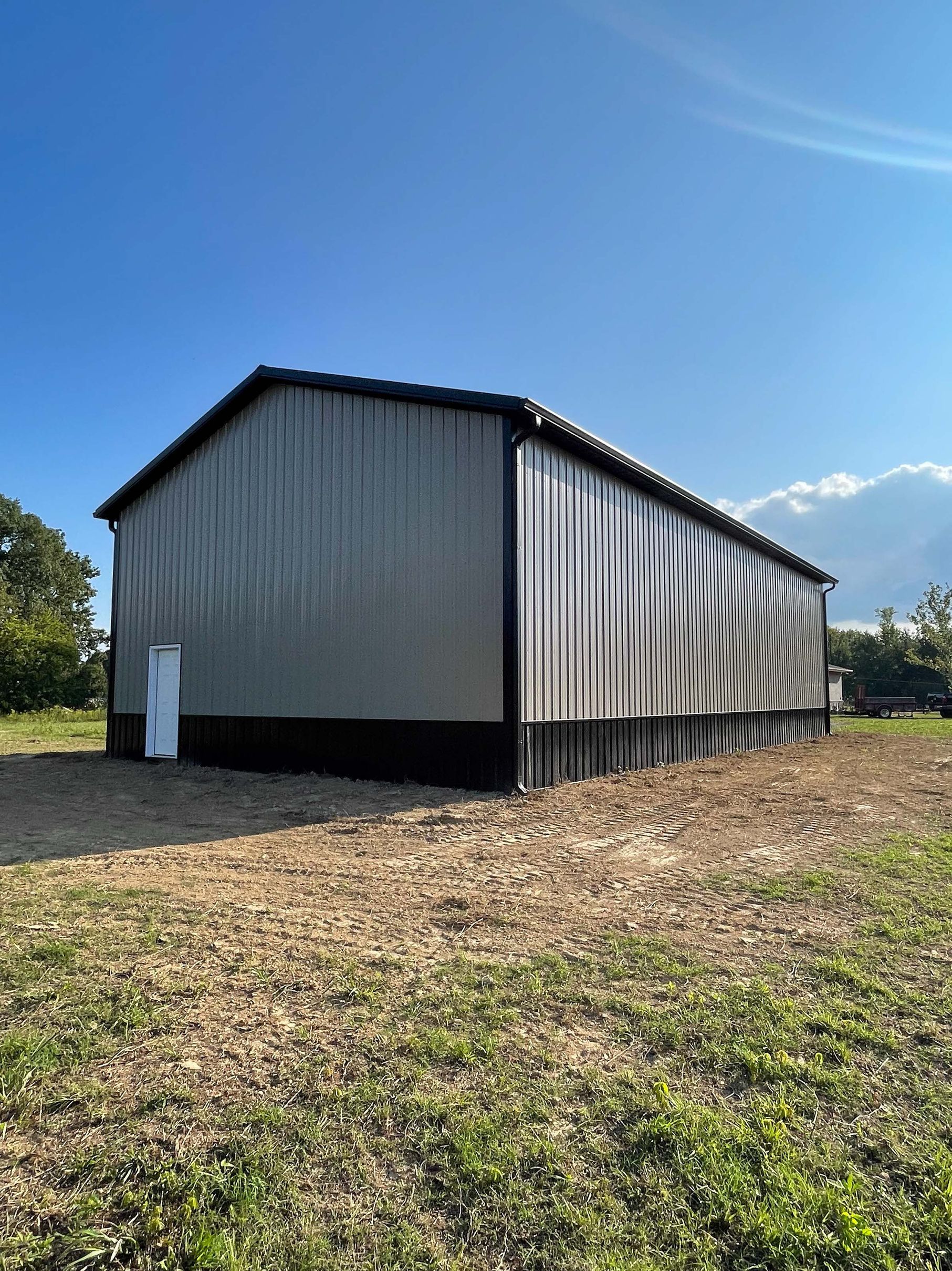 A large metal building is sitting in the middle of a grassy field.