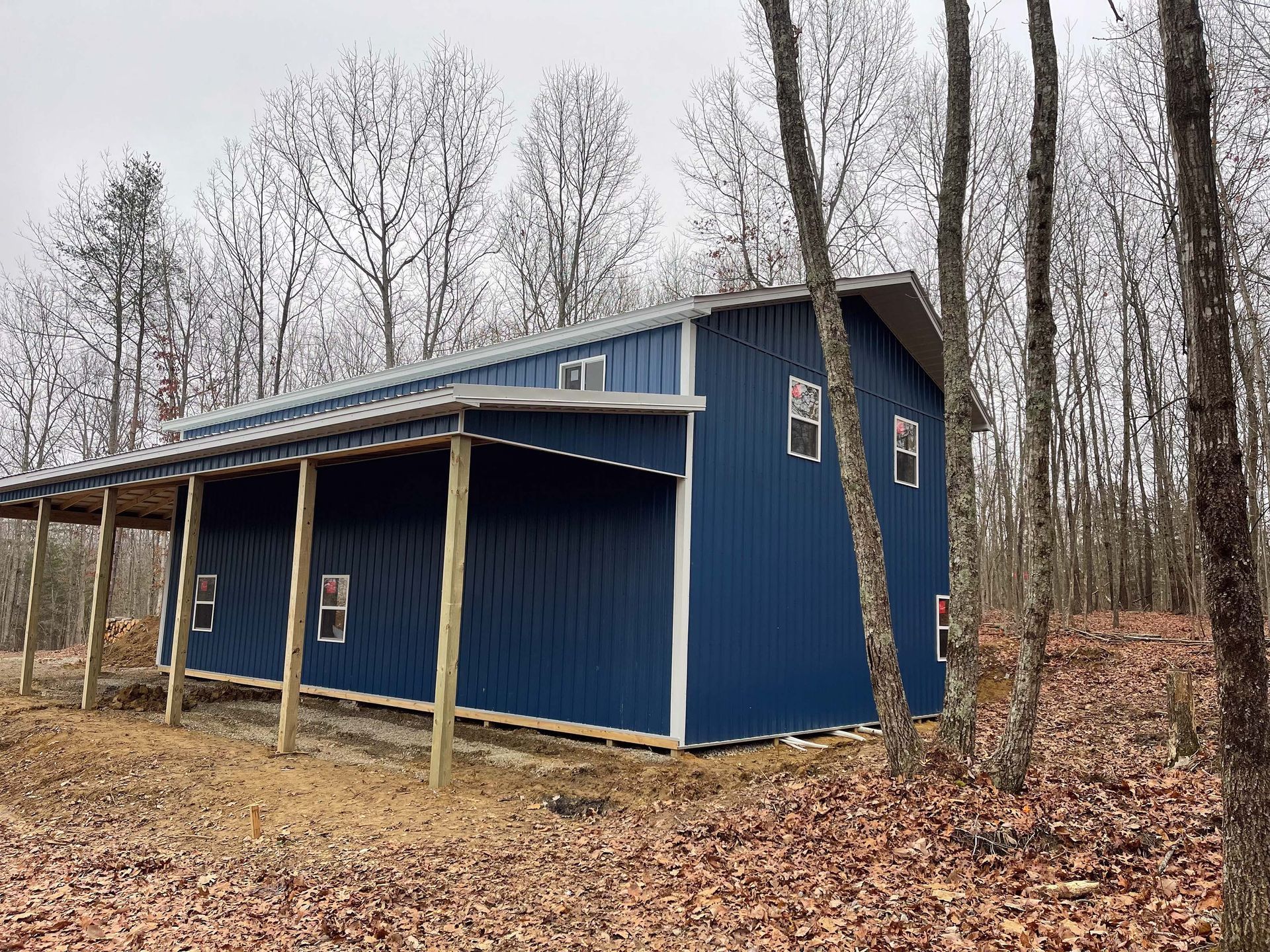 A blue building with a porch in the middle of a forest.