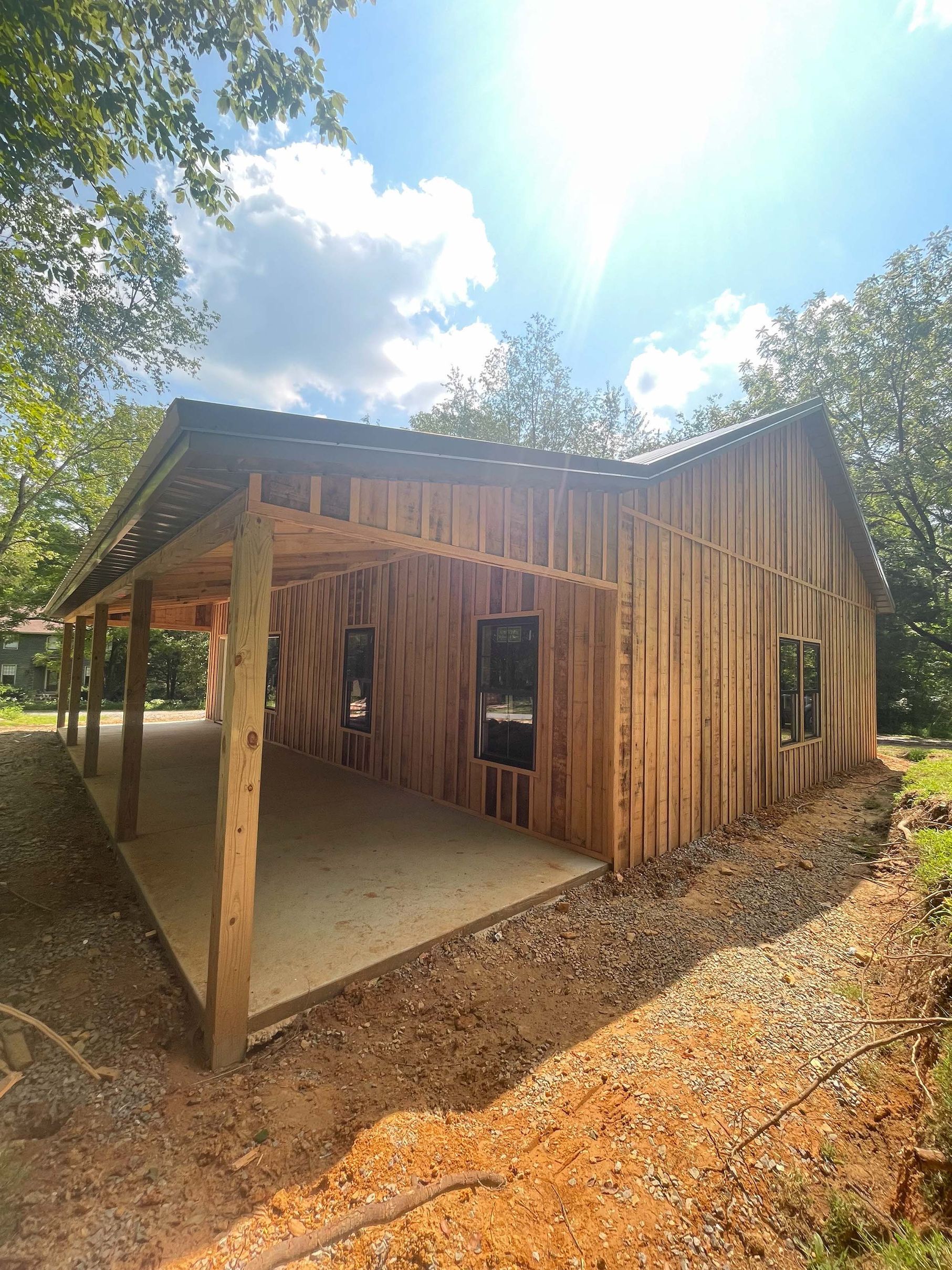 A wooden house is being built in the middle of a dirt field.