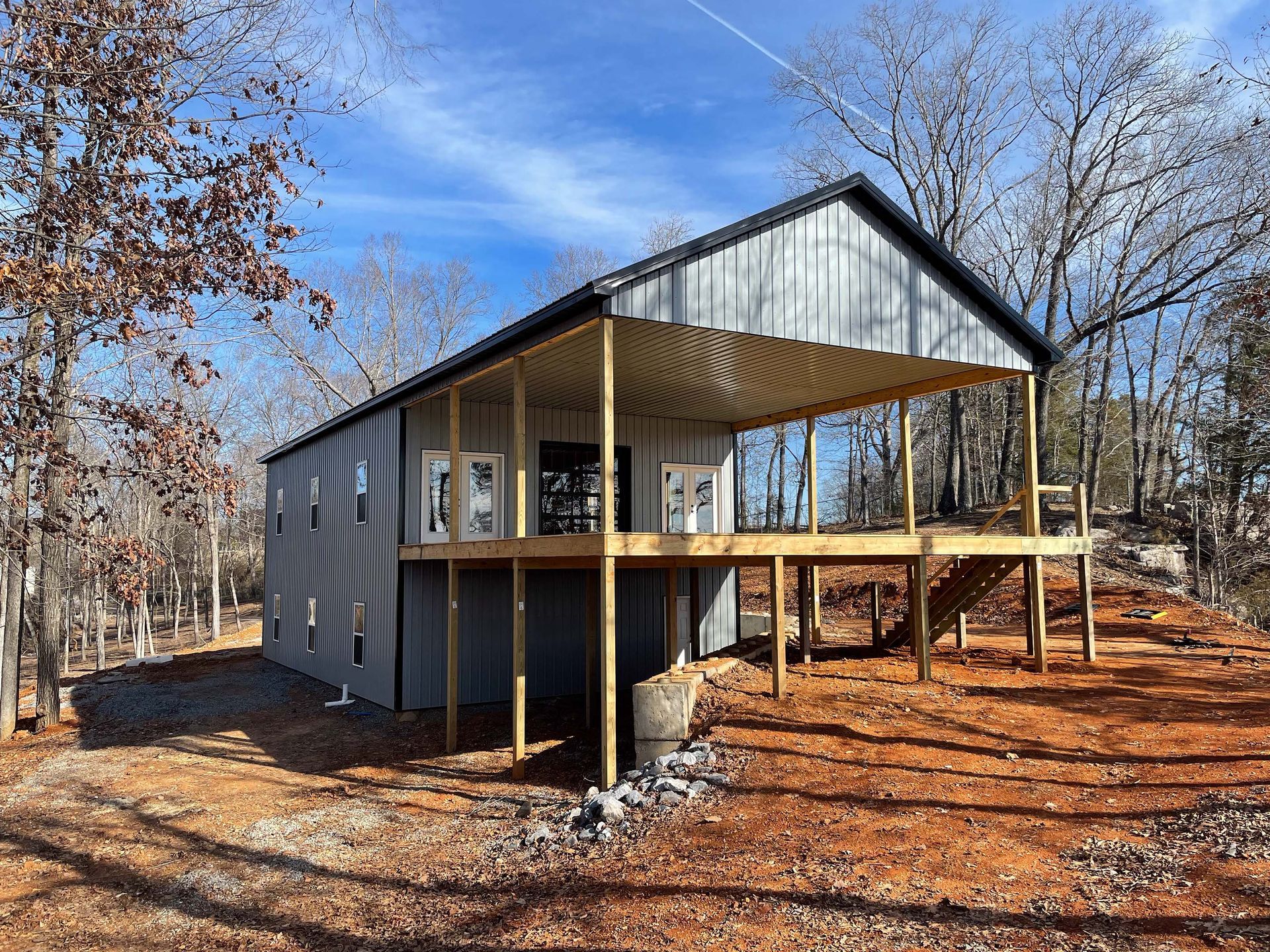 A large metal building with a wooden deck is sitting on top of a dirt hill.