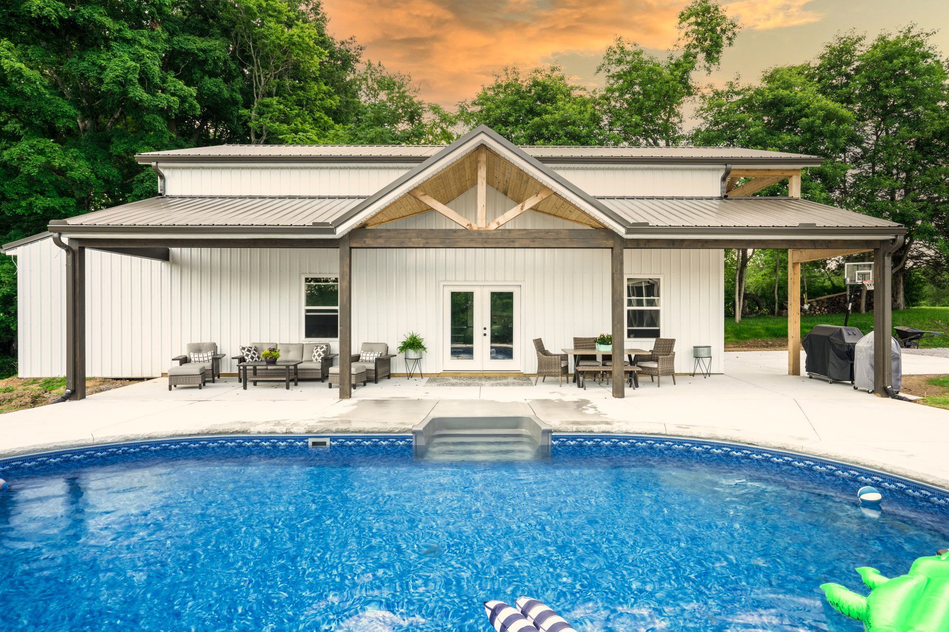 A white house with a swimming pool in front of it.