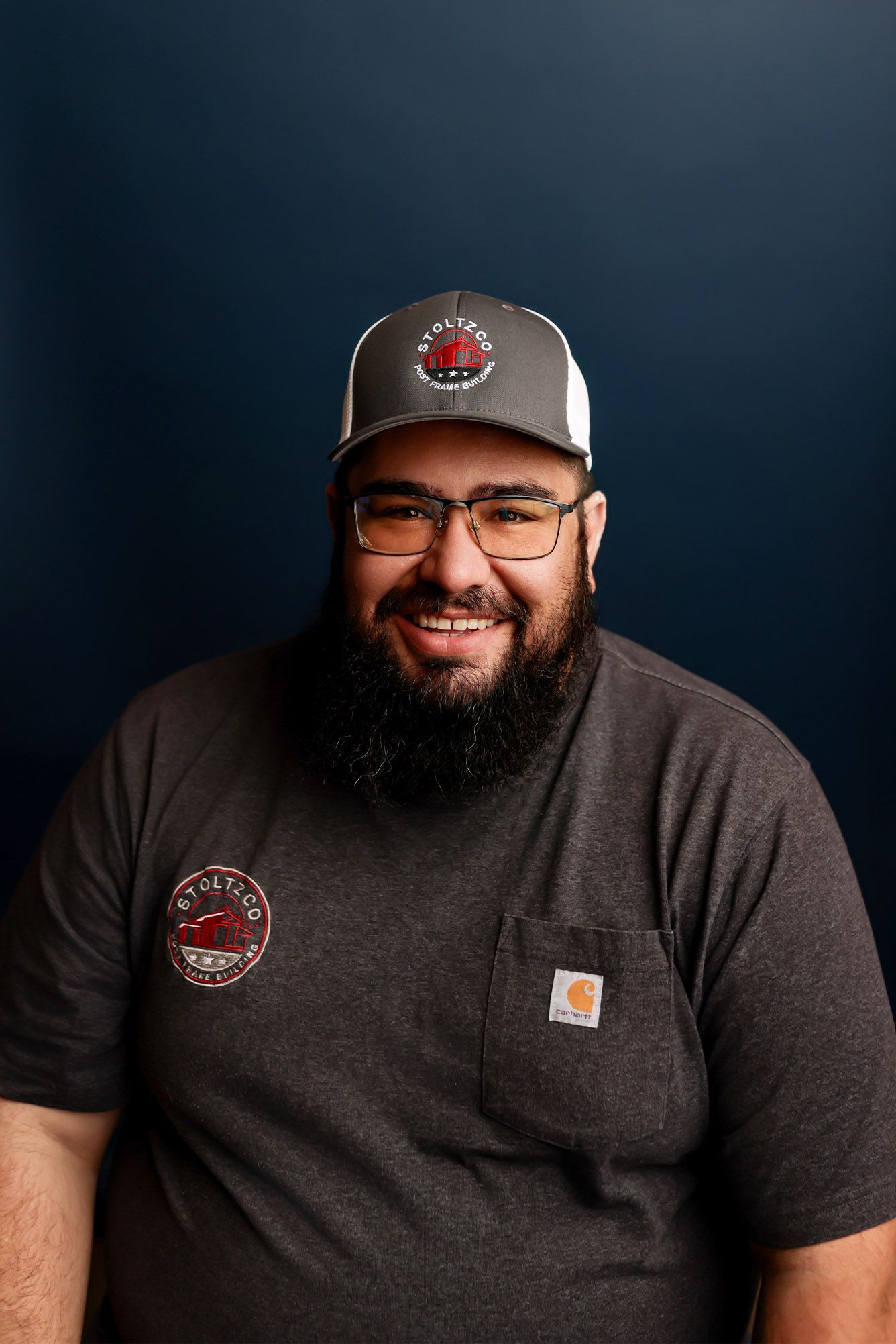 A man with a beard is wearing a hat and glasses.