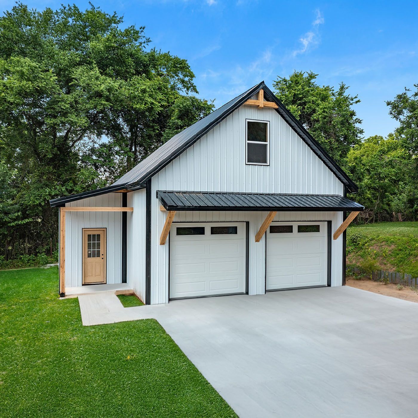 A white garage with three doors and a driveway in front of it