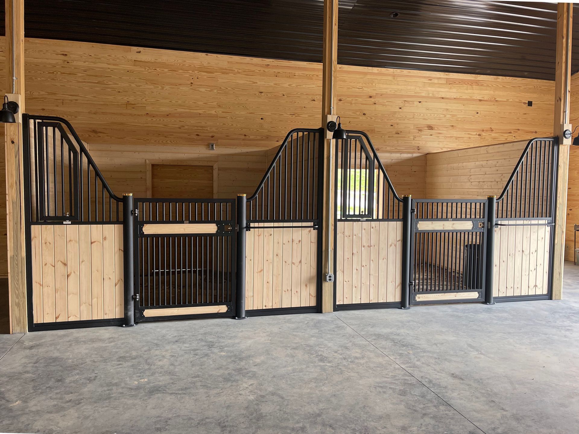 A horse stable with wooden stalls and black gates