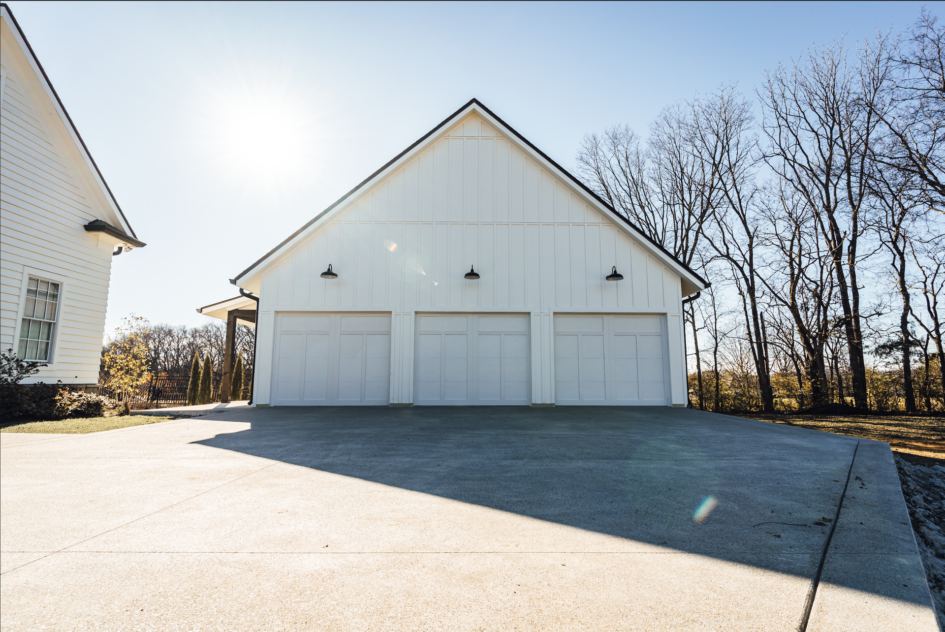 A white garage with three doors and a driveway in front of it