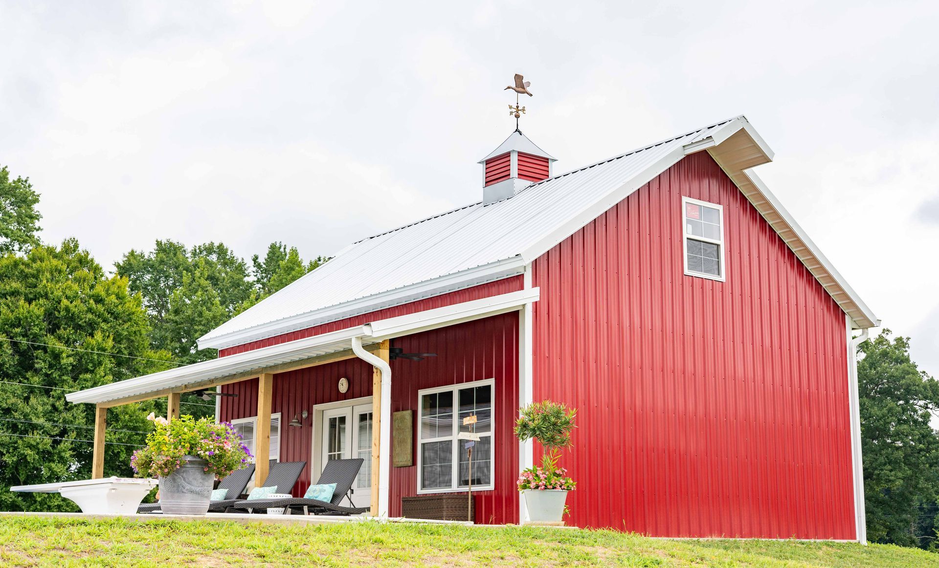 A red barn with a white roof and a porch.