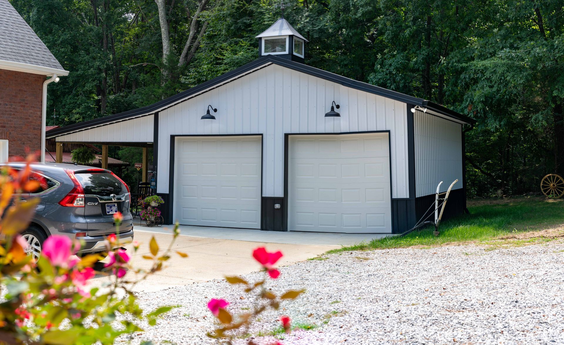 A white garage with two garage doors and a car parked in front of it.