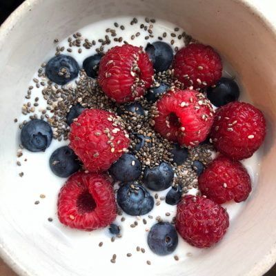 a bowl of yogurt with raspberries blueberries and chia seeds