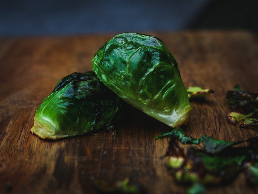two brussels sprouts are sitting on a wooden cutting board .