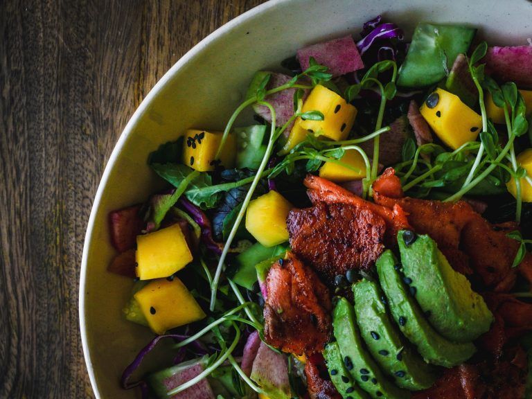 a close up of a salad in a bowl on a wooden table .