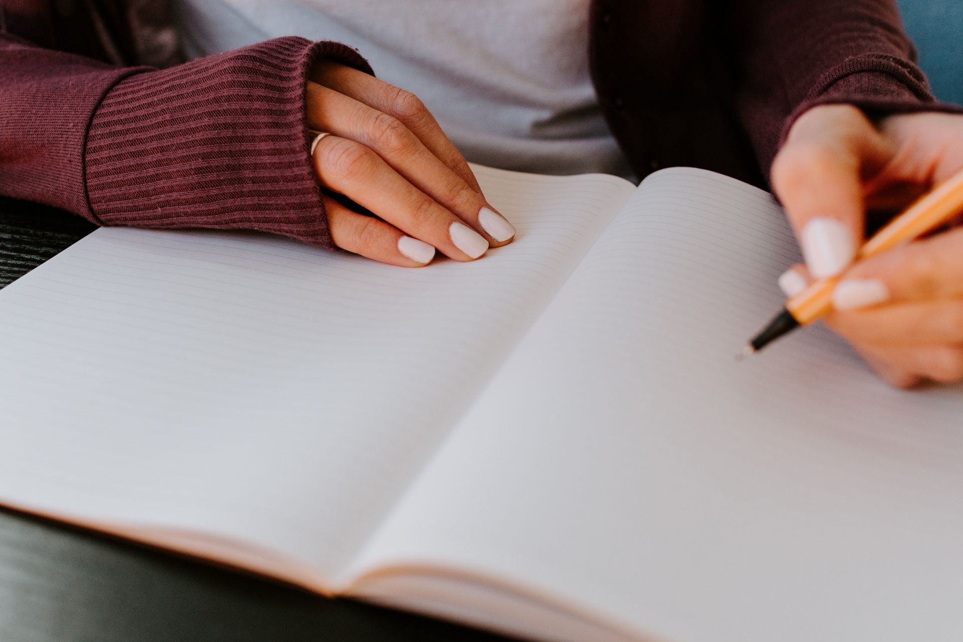 a woman is writing in a notebook with a pen .