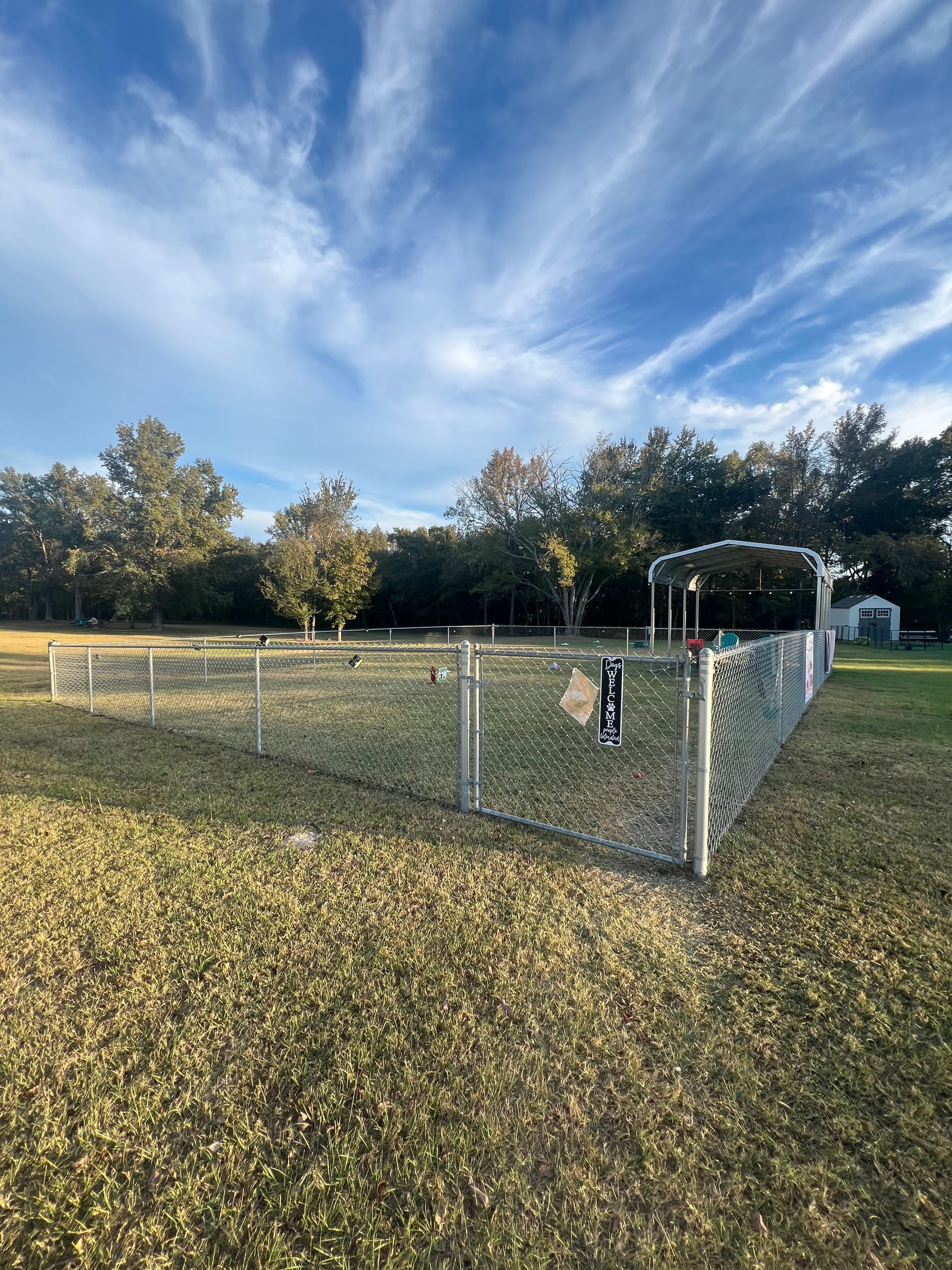 A chain link fence surrounds a grassy field in a park.
