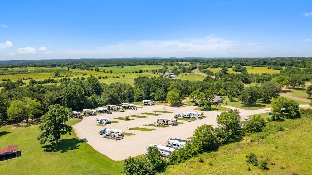 An aerial view of a park with a lot of rvs parked in a field.
