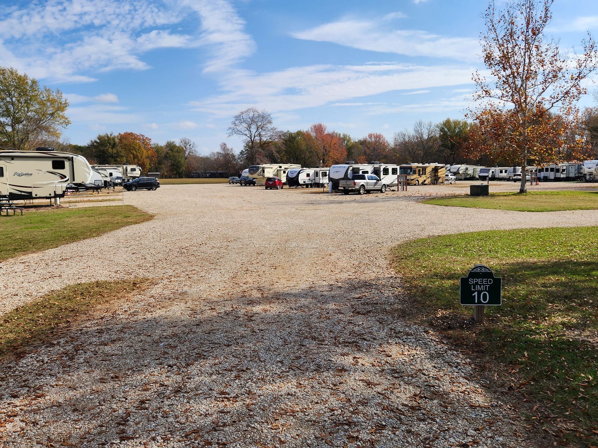 A lot of rv 's are parked in a gravel lot.