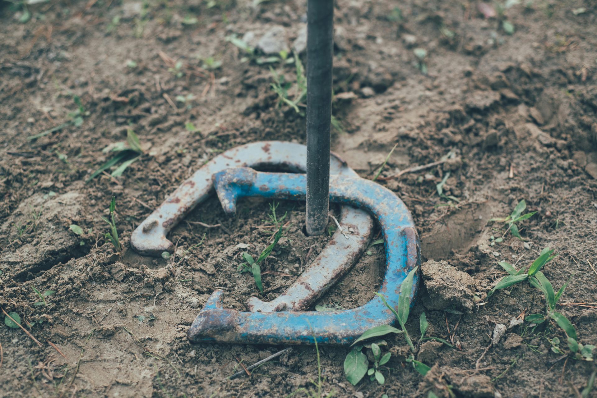 A horseshoe is sitting in the dirt next to a pole.