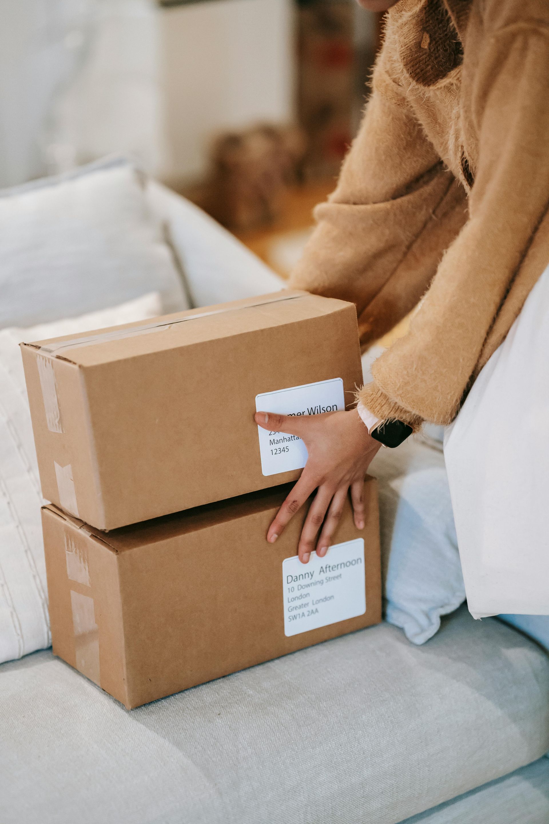 A woman is sitting on a couch holding two cardboard boxes.