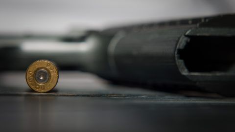 A bullet and gun lay next to each other on a table