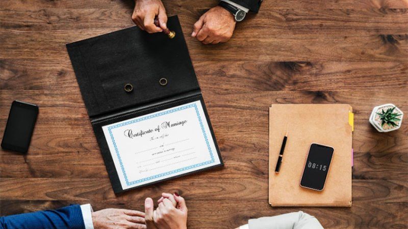 A couple of people are sitting at a table with a certificate on it.