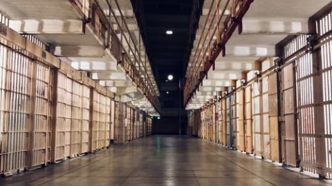 A prison hallway with cells on either side