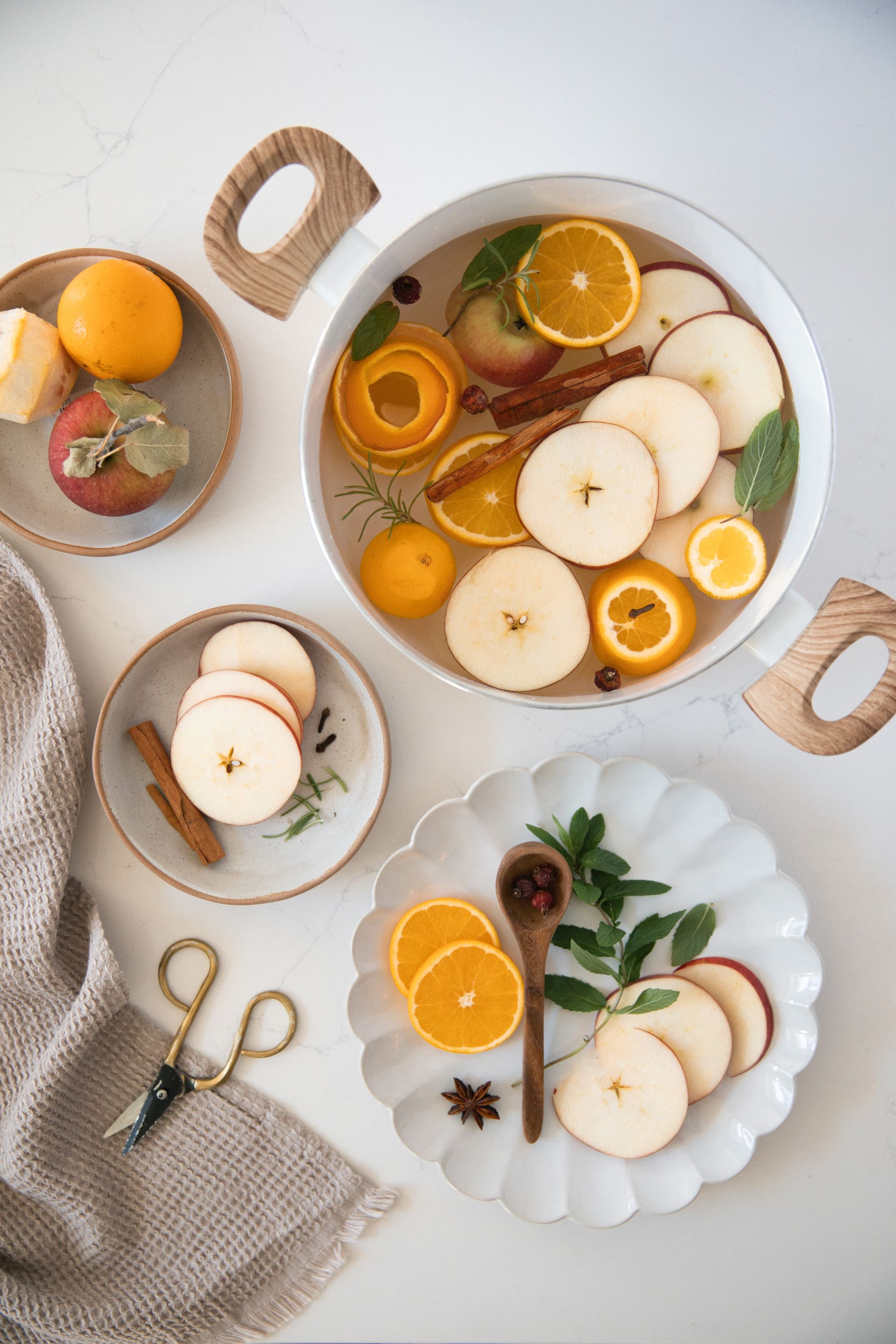a pot of mulled wine with apples, oranges, and cinnamon sticks on a table.
