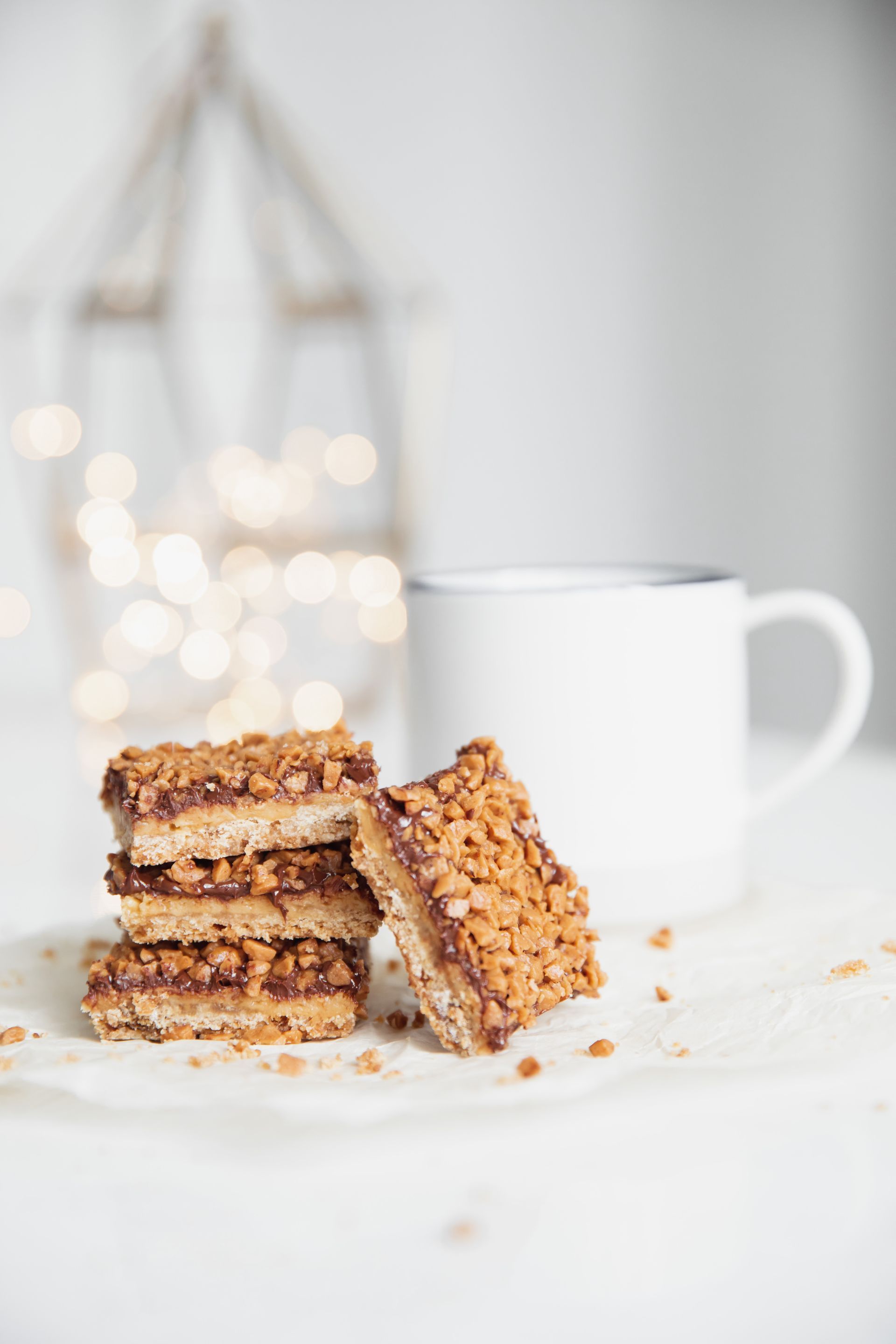 a white plate topped with a stack of toffee crunch bars next to a cup of coffee