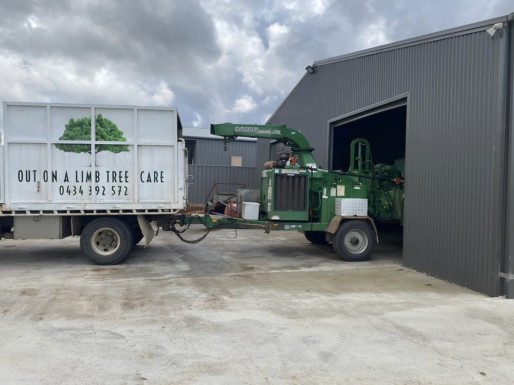 A Truck With A Trailer Attached To It Is Parked In Front Of A Building — Out On A Limb Tree and Garden Care In Broulee, NSW