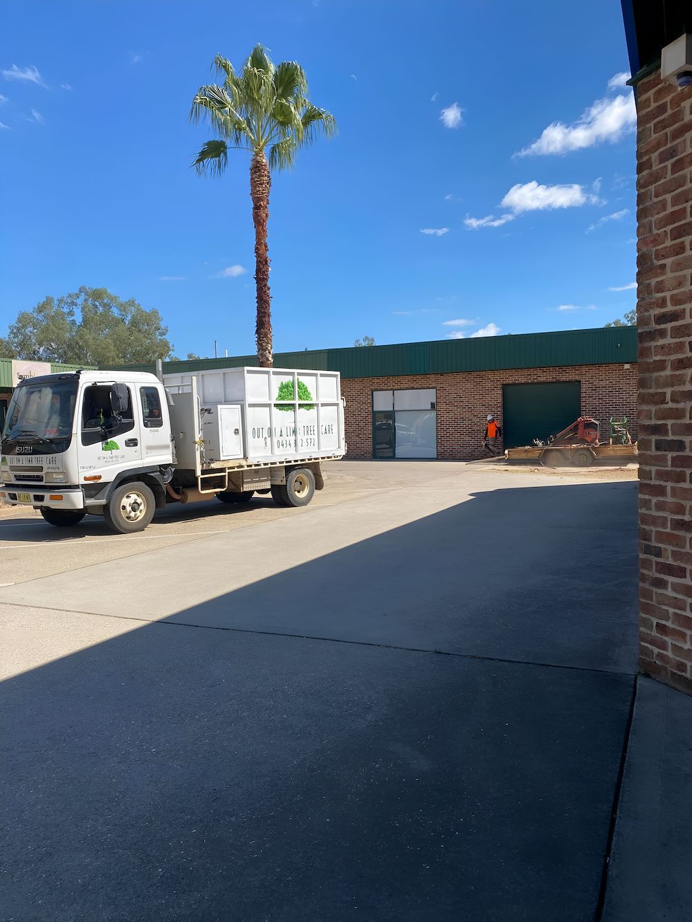 A White Truck Is Parked In Front Of A Brick Building — Out On A Limb Tree and Garden Care In Broulee, NSW