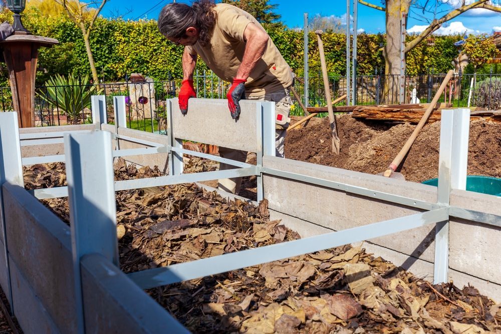 A Man Is Working On A Fence In A Garden — Out On A Limb Tree and Garden Care In Broulee, NSW