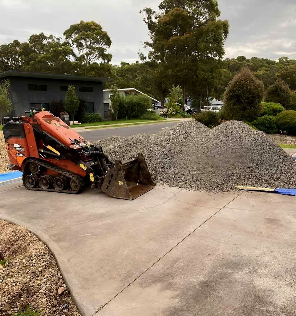 A Bulldozer Is Sitting On The Side Of A Road Next To A Pile Of Gravel — Out On A Limb Tree and Garden Care In Broulee, NSW