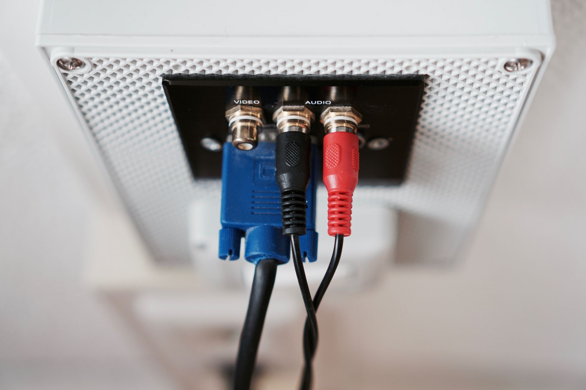Back of a monitor with blue, black, and red cables plugged into ports