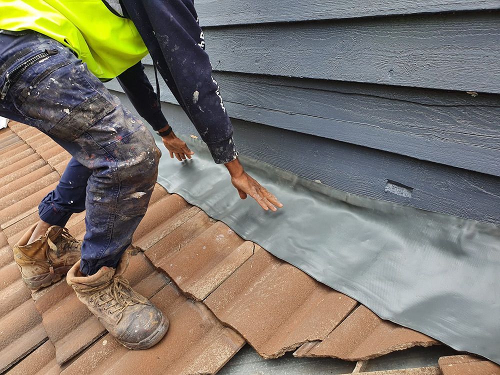 Person Is Applying the Leak Protection Layer On The Roof — ACT Roofing in Ngunnawal, ACT