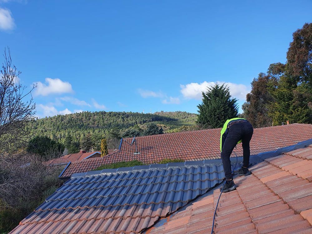 Person Is Painting The Roof With Spray Gun — ACT Roofing in Ngunnawal, ACT