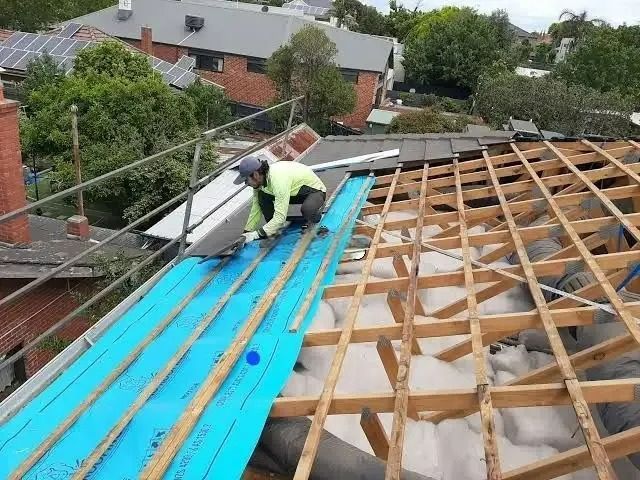 A Man Is Applying The Wooden Beams On The Roof Of A Building — ACT Roofing in Ngunnawal, ACT