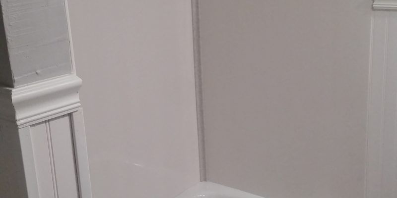 White paneled wall corner with decorative molding and trim in a light gray room.
