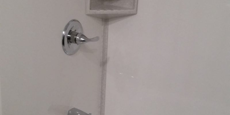 Chrome shower valve on a white tiled bathroom wall