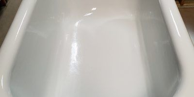 Close-up of a white porcelain sink basin with curved edges and chrome faucet reflections