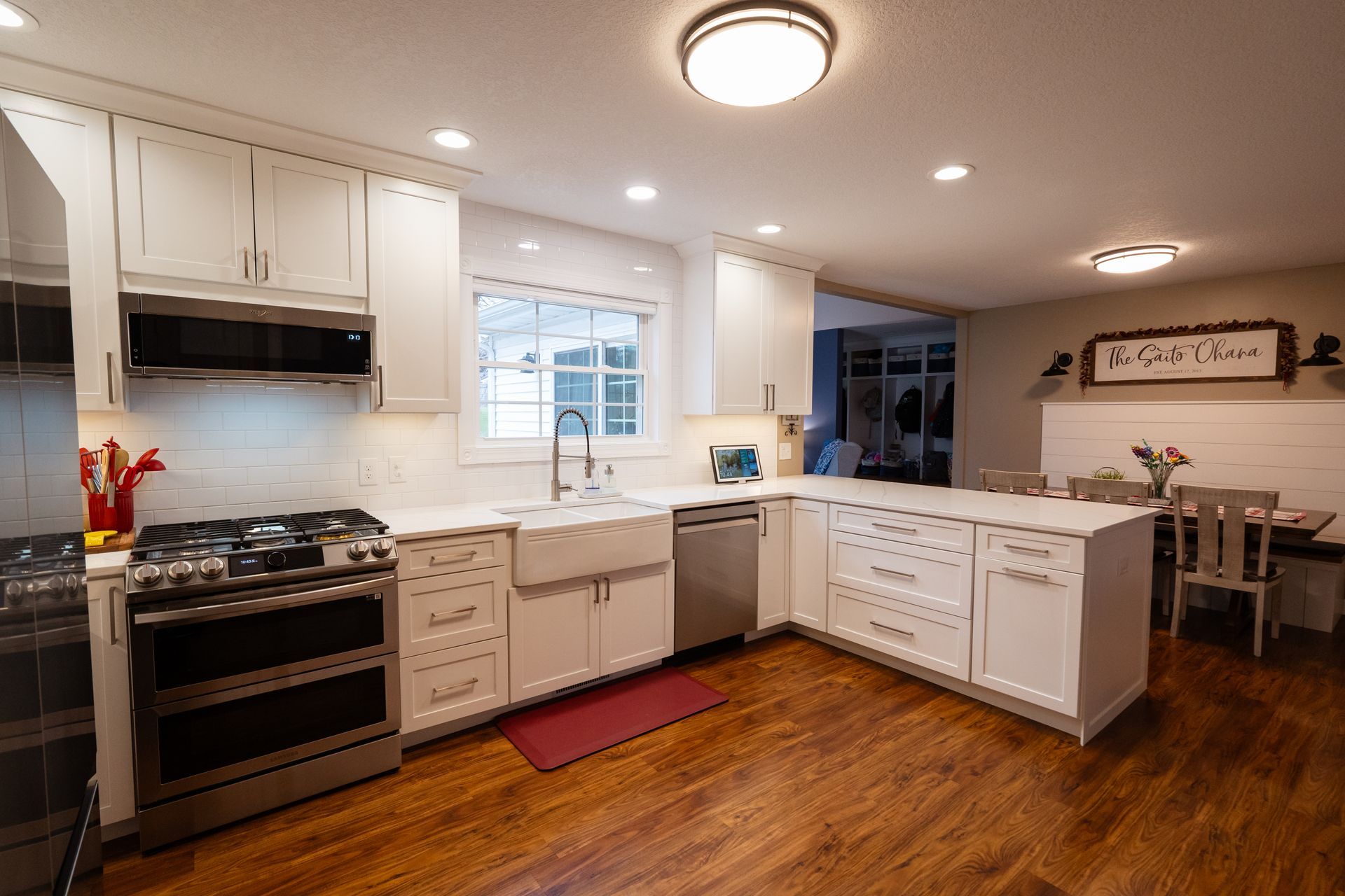 Bright white kitchen with stainless stove, island, farmhouse sink, and wooden floors