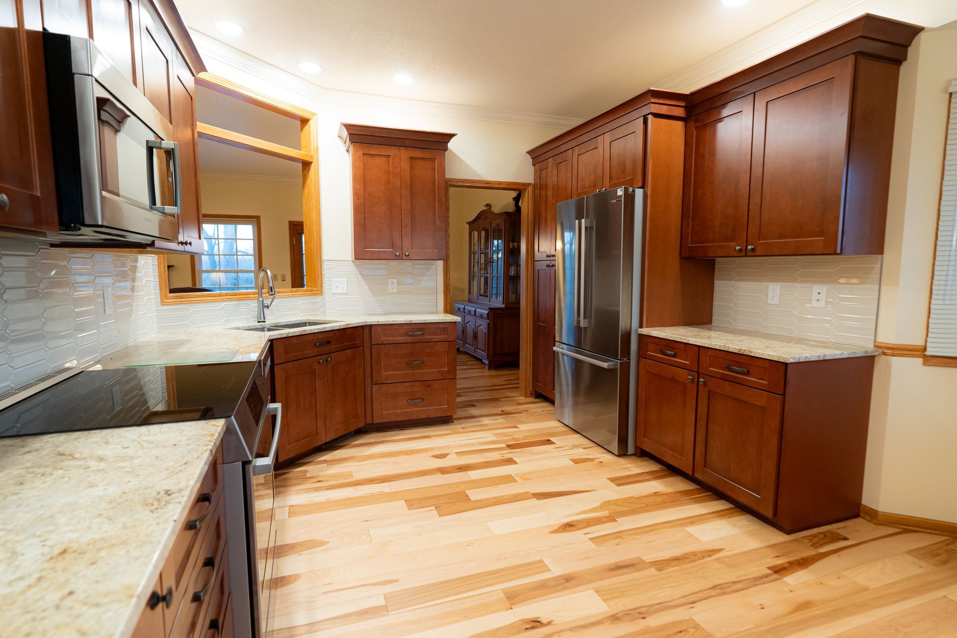 Spacious kitchen with cherry wood cabinets, stainless steel appliances, light countertops, and hardwood floors
