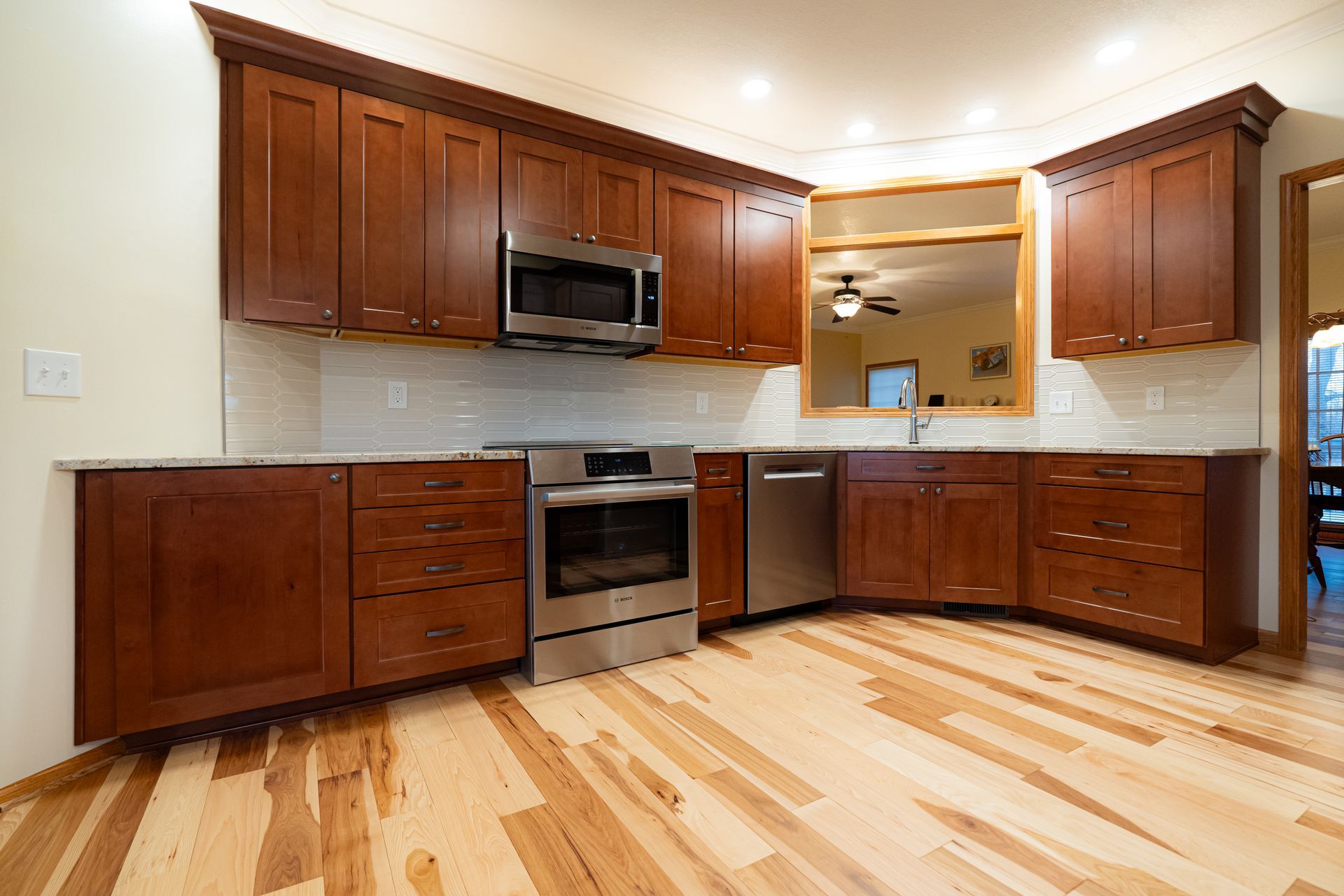 Modern kitchen with cherry cabinets, stainless steel appliances, and light wood floors
